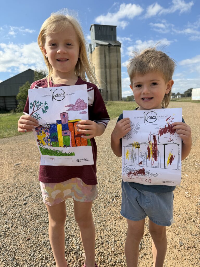 Two children holding up their Little Art Legends colouring sheets